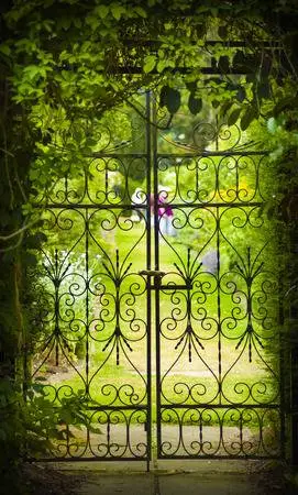 36167873-a-gate-hides-a-green-flower-filled-garden.webp