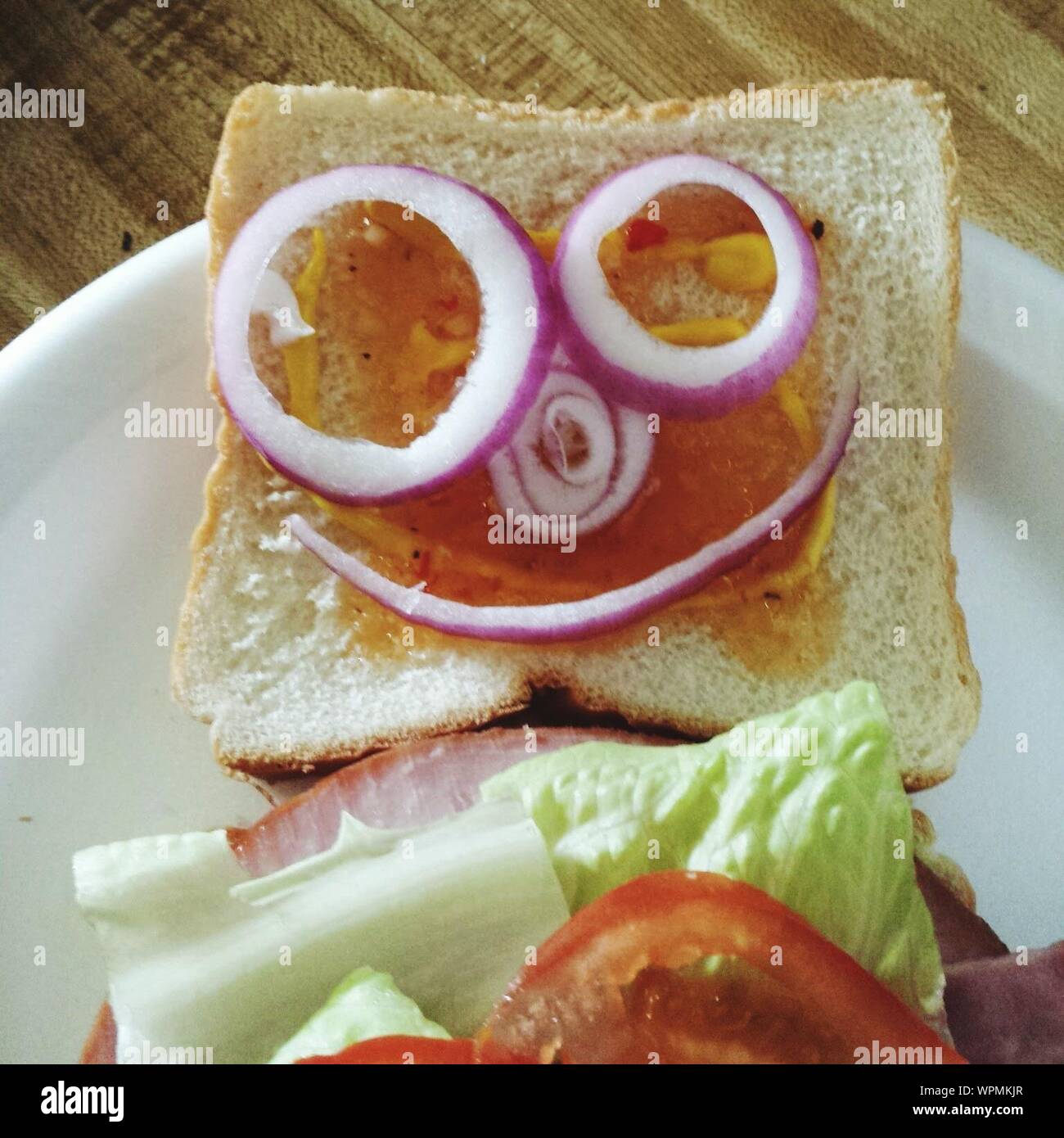 close-up-of-anthropomorphic-smiley-face-made-from-onion-slices-on-bread-WPMKJR.jpg